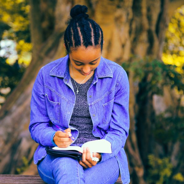 Woman sitting on a park bench writing in a journal